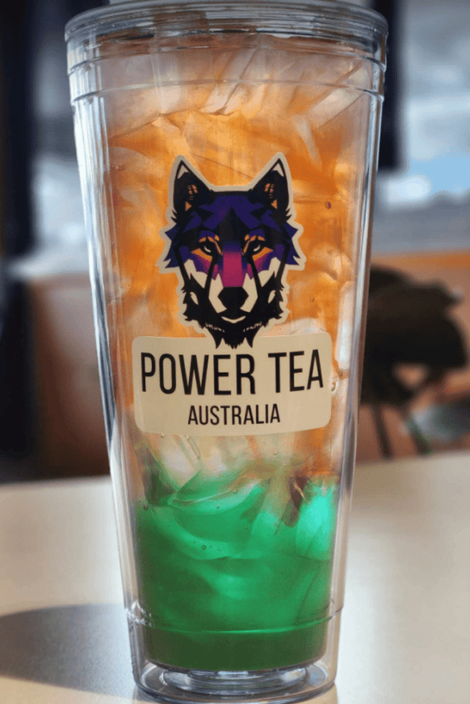 A picture of a full cup of Power Energy Tea with green and apricot coloured tea swirling together